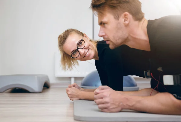 Leende kvinna på gymmet tittar sportsmanen — Stockfoto