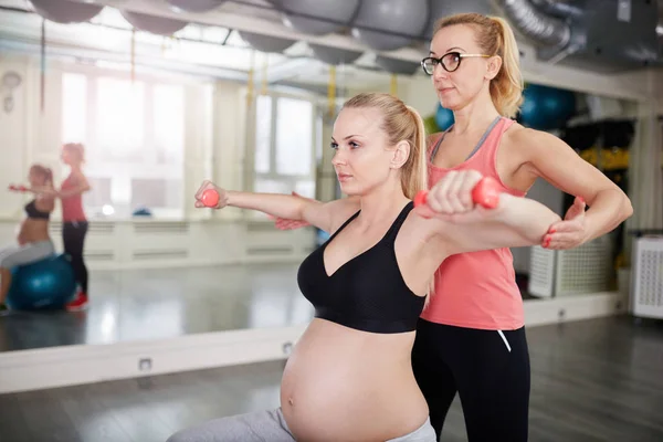 Hamile kadın kişisel antrenör ile ağırlık kaldırma — Stok fotoğraf