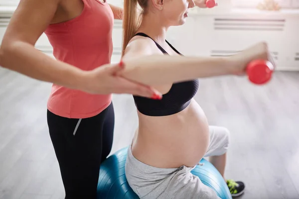 Kobieta w ciąży na piłkę, podnoszenie ciężarów z osobistym trenerem — Zdjęcie stockowe