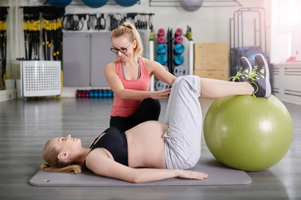 Gravid kvinna träning med coach med pilates boll — Stockfoto