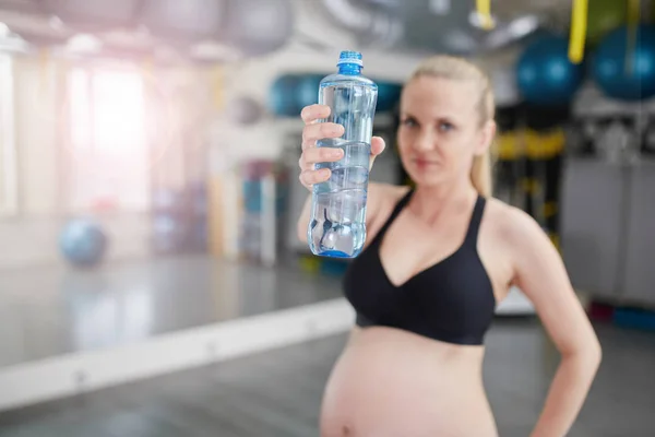 Kobieta w ciąży, trzymając niebieska butelka wody — Zdjęcie stockowe