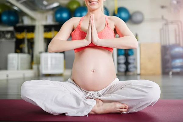 Szczęśliwy w ciąży kobieta siedząc w pozycji lotosu, składane jej ręce — Zdjęcie stockowe