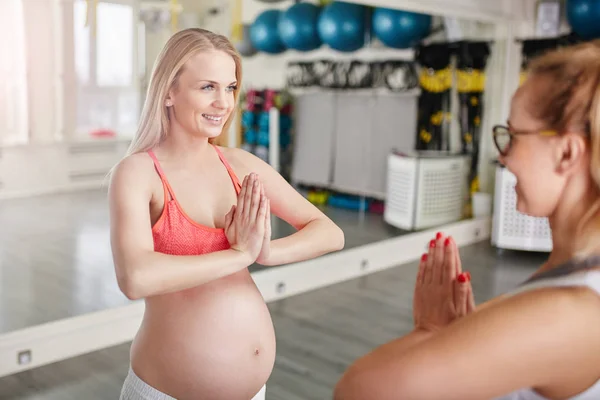 Счастливая беременная женщина складывает руки перед своим тренером — стоковое фото