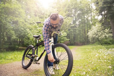 Parkta bisiklet tekerleği tamir eden genç adam.