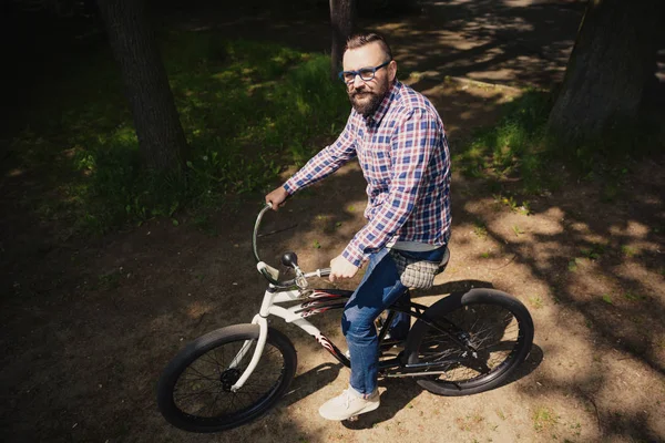 Jonge moderne man zit op de fiets in het park — Stockfoto