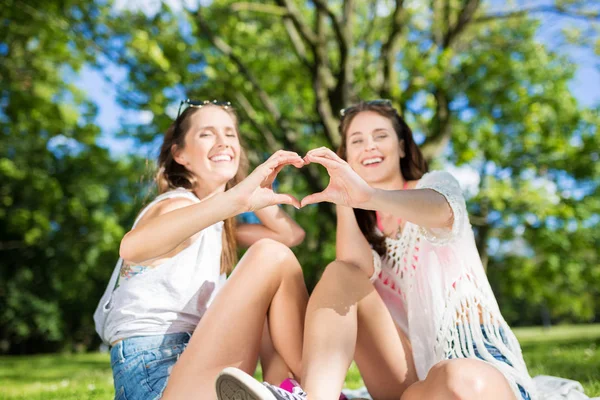 Glückliche Freundinnen draußen machen Herzenszeichen — Stockfoto