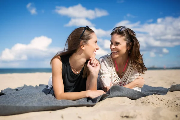 Duas amigas felizes deitadas na praia falando — Fotografia de Stock