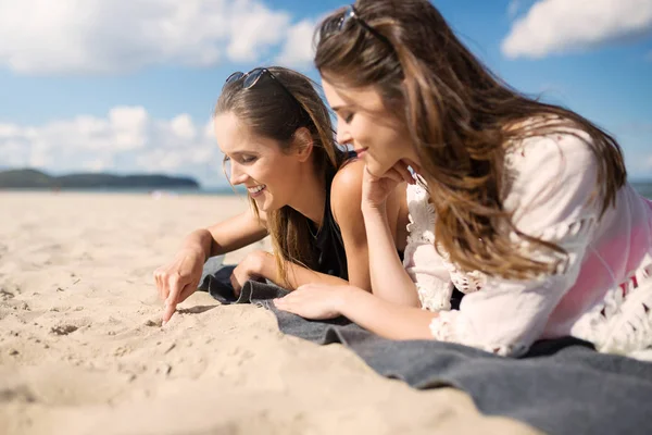 Duas belas mulheres felizes deitadas na praia — Fotografia de Stock