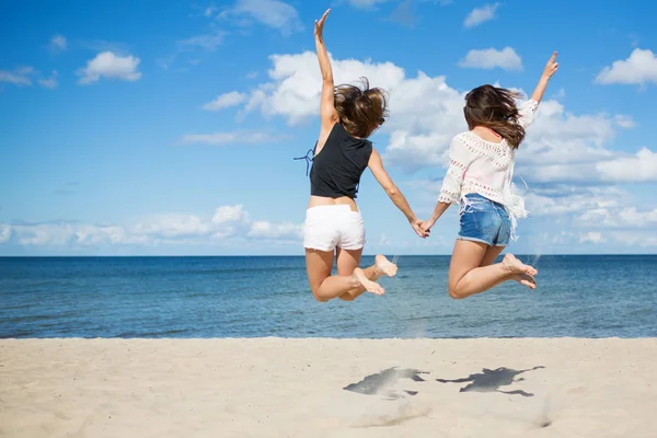 Amigos do sexo feminino pulando na praia de mãos dadas — Fotografia de Stock