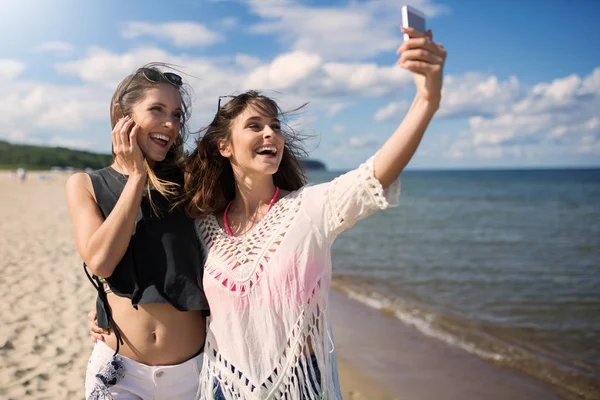 Duas mulheres felizes na praia tirando selfie pelo celular — Fotografia de Stock