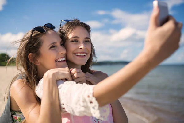 Dvě krásné kamarádky při selfie na pláži — Stock fotografie
