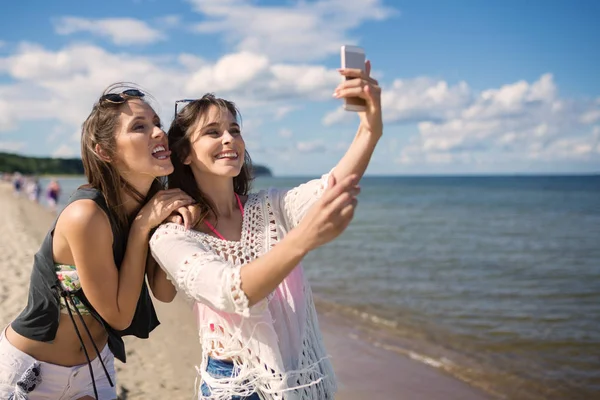 Duas meninas felizes tomando selfie na praia se divertindo — Fotografia de Stock