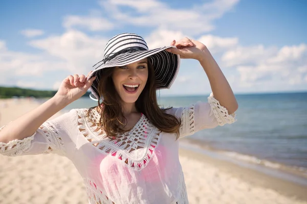 Giovane donna felice in cappello in posa per foto sulla spiaggia — Foto Stock