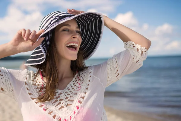 Щаслива красива жінка в капелюсі на пляжі дивиться далеко — стокове фото
