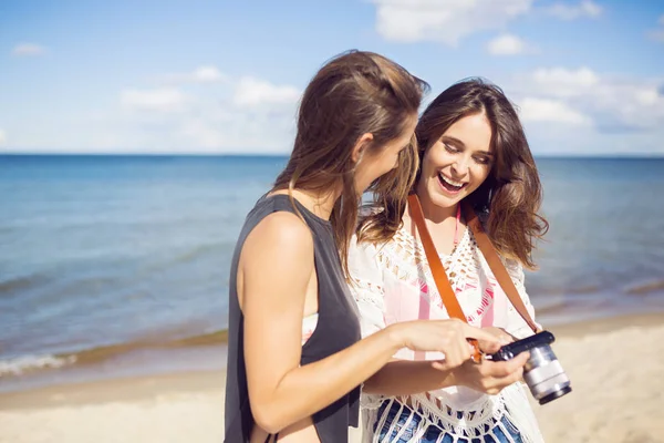 Mulheres felizes em pé na praia assistindo fotos na câmera — Fotografia de Stock