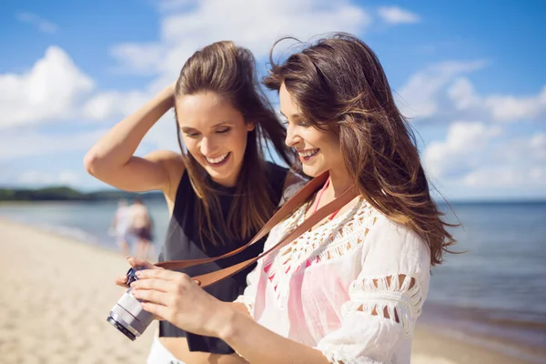 Две красивые женщины на пляже смотрят фотографии на камеру — стоковое фото