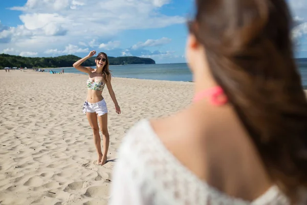 Щаслива дівчина стоїть на пляжі посміхається подрузі — стокове фото
