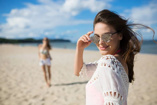 Felice bella donna in occhiali da sole in piedi sulla spiaggia con l'amico — Foto Stock