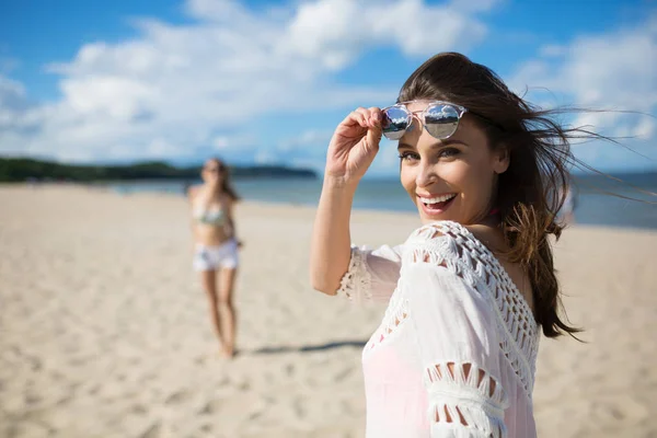Щаслива красива жінка, що стоїть на пляжі зі сміхом друга — стокове фото