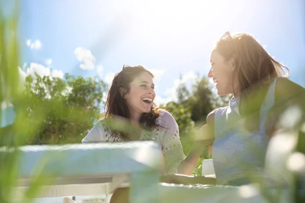 Zwei hübsche Mädchen sitzen am Cafétisch und reden und lachen — Stockfoto