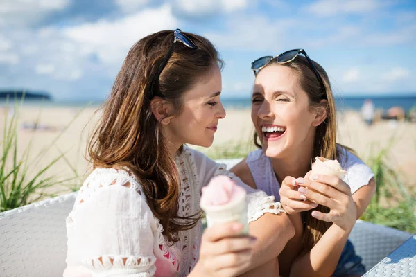 Zwei glückliche Freundinnen sitzen draußen und halten Eis — Stockfoto