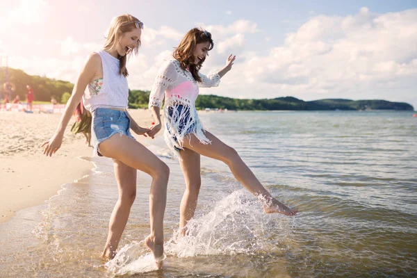 Feliz amigos do sexo feminino de mãos dadas salpicando água — Fotografia de Stock