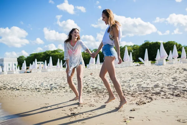 Щасливі красиві жінки тримають руки, ходять на пляжі — стокове фото