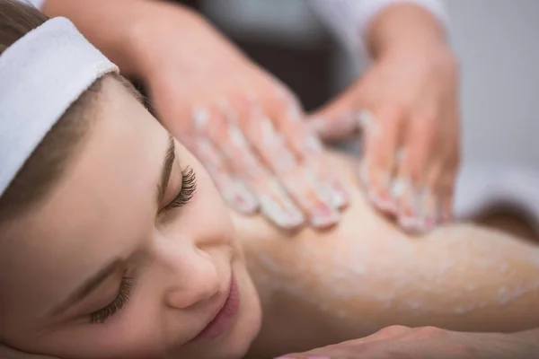 Joven sonriente mujer consiguiendo reafirmante azúcar scrub terapia en su b — Foto de Stock