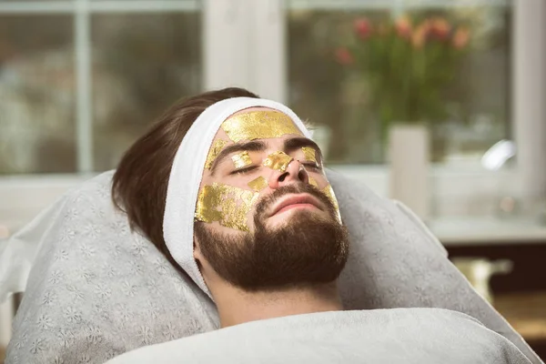 Miesten kultainen naamio terapiaa kosmetologi — kuvapankkivalokuva