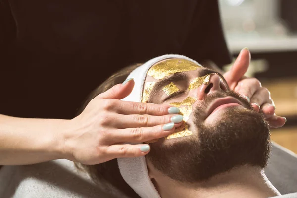 Mäns guld mask terapi på kosmetologs — Stockfoto