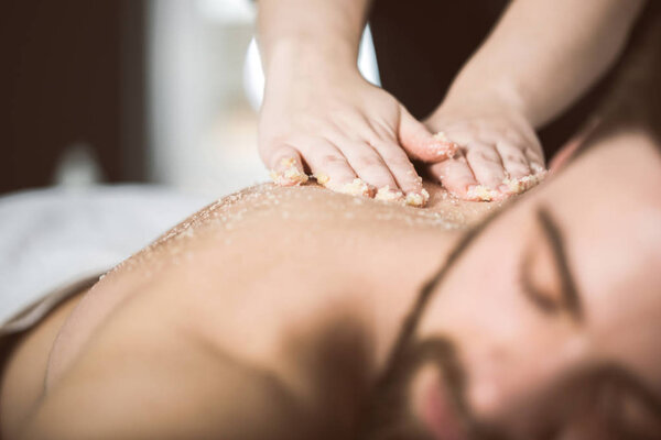 Man relaxing during a salt scrub beauty therapy