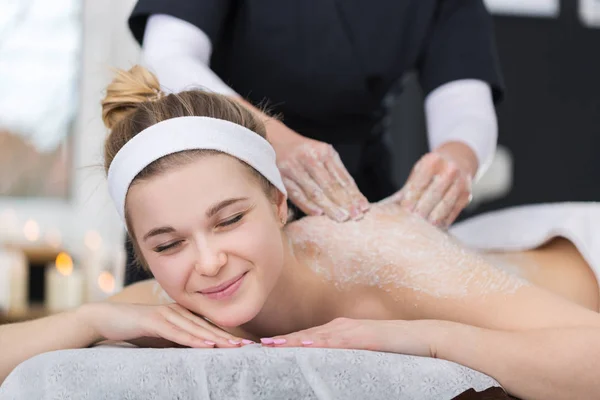 Vrouw krijgt exfoliërende zout scrub massage bij de schoonheidsspecialiste Stockfoto