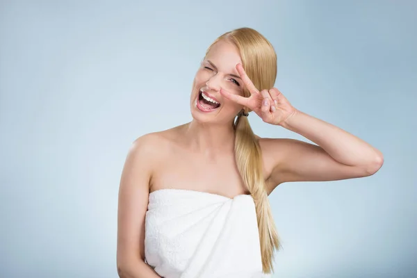 Счастливая женщина в полотенце показывает знак мира смеется — стоковое фото