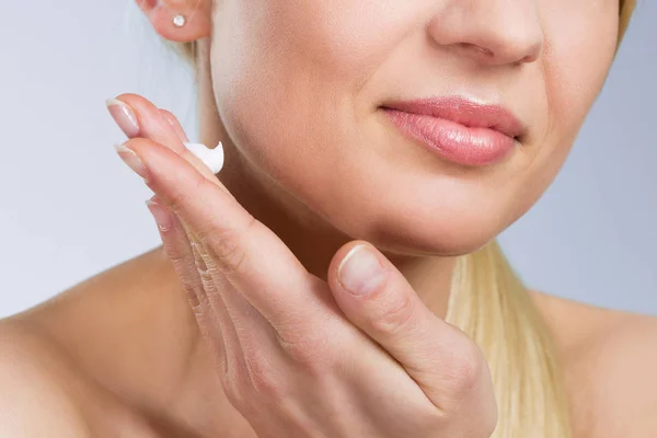 Mujer aplicando crema en la cara —  Fotos de Stock