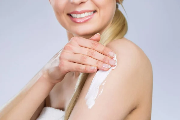 Mujer feliz aplicando crema en el brazo —  Fotos de Stock