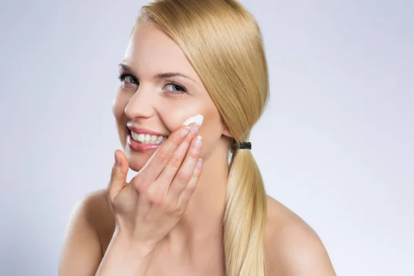 Hermosa mujer feliz aplicando crema en la cara —  Fotos de Stock