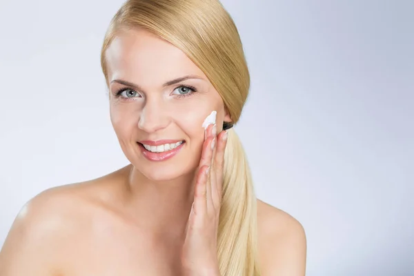 Mujer feliz aplicando crema en la cara —  Fotos de Stock