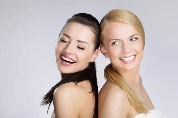 Zwei hübsche Frauen lehnen sich lachend aneinander — Stockfoto