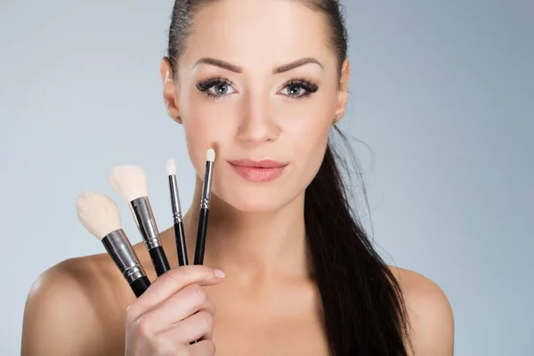 Beautiful woman holding make up brushes — Stock Photo, Image