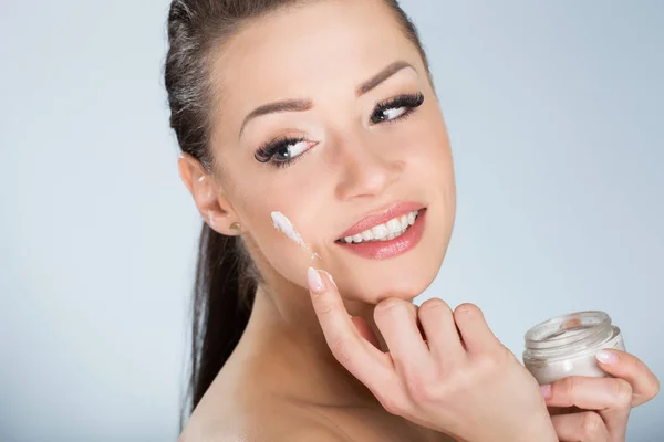 Hermosa mujer sonriente que humedece la cara con crema —  Fotos de Stock