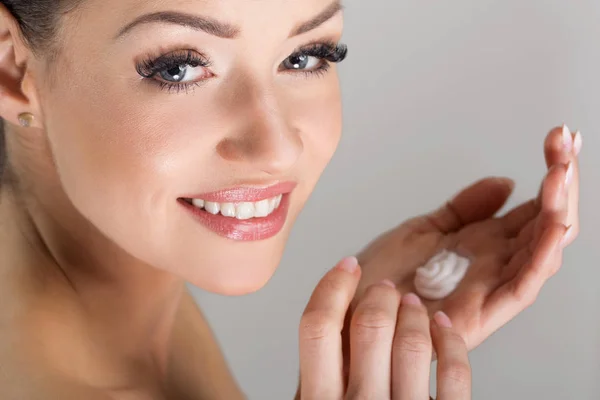 Mulher bonita segurando creme na mão sorrindo feliz — Fotografia de Stock