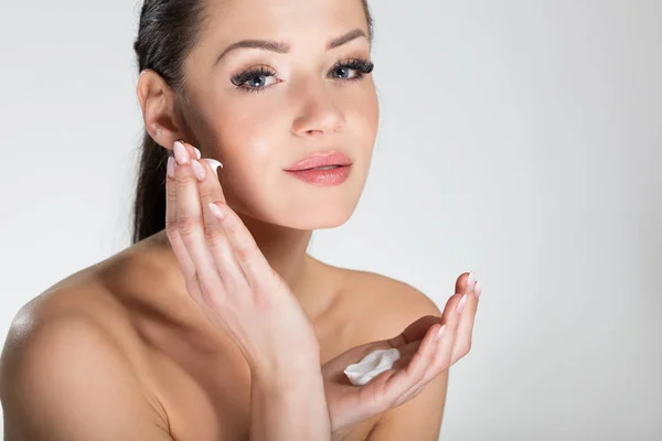 Mulher muito sorridente aplicando creme no rosto — Fotografia de Stock