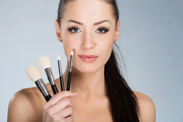 Hermosa mujer sosteniendo maquillaje cepillos — Foto de Stock