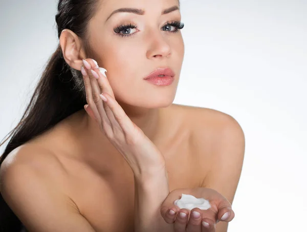Hermosa mujer seria aplicando crema en la cara —  Fotos de Stock