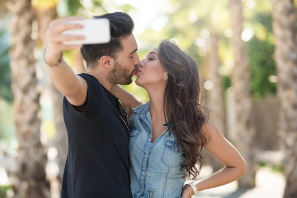 Jovem casal beijando uns aos outros posando para selfie — Fotografia de Stock