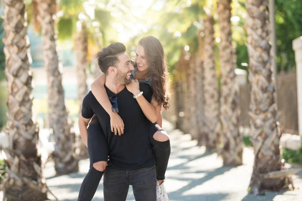 Joven hombre feliz sosteniendo a su novia en la espalda — Foto de Stock