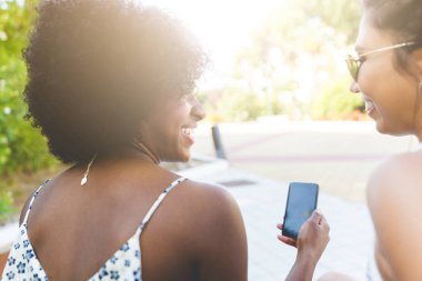 İki mutlu kız gülerek dışında smartphone kullanarak