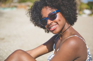 Güzel afro Amerikan kadın gülümseyerek dışında oturuyordu
