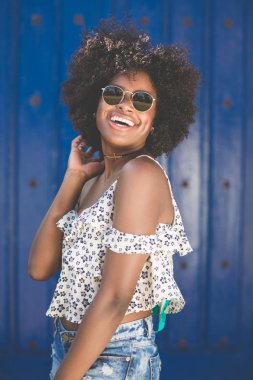 Mavi arka plan gülüyor üzerinde genç afro Amerikalı kadın