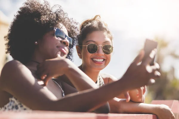 Две счастливые женщины смотрят на смартфон снаружи — стоковое фото